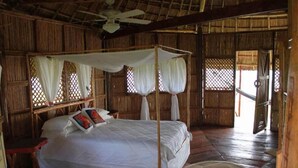 Une chambre dotée d’un lit à baldaquin, de linge de lit blanc et d’un ventilateur de plafond.