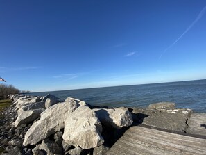 A rocky shoreline with large boulders and a wooden boardwalk leading to the water.