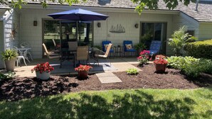 Un patio con una mesa y sillas, una sombrilla azul y plantas en macetas.