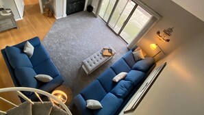 Un salón amplio con televisor grande, chimenea y balcón.