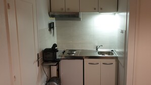 A compact kitchen with white cabinets, a stainless steel sink, and a built-in range hood. - Apartment F2, 4 pers, ideally located classified 2*, wifi  (Courseulles-sur-Mer)