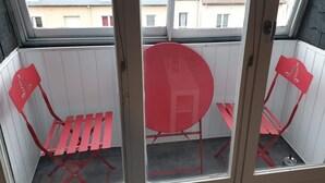 A balcony with a red table and two red chairs. - Apartment F2, 4 pers, ideally located classified 2*, wifi  (Courseulles-sur-Mer)