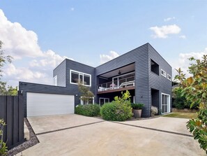 A modern two-story house with a garage, a balcony, and a well-maintained garden.