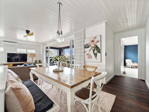 A modern living room with a dining area, a television, and a large window.