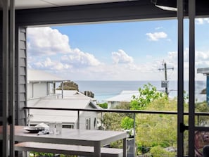 Een balkon met uitzicht op de oceaan en huizen.