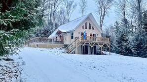 A cabin with a wooden deck and stairs leading to a covered porch.