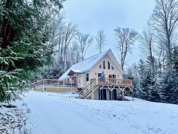 Une cabane dotée d’une terrasse en bois et d’un escalier menant à un porche abrité.
