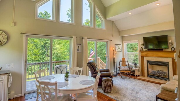 A spacious living room with a fireplace, a television, and a dining area with a view of the outdoors.