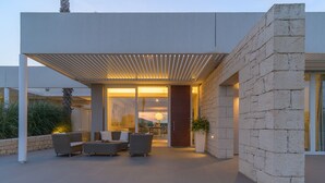 A modern outdoor living area with a covered patio, stone walls, and comfortable seating. - Venere, villa with private pool and  gym near the sea in Marina di Ragusa (Marina di Ragusa)
