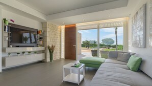 A modern living room with a large flat-screen TV, a sofa, a coffee table, and a view of the outdoors. - Venere, villa with private pool and  gym near the sea in Marina di Ragusa (Marina di Ragusa)