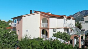 A two-story building with a balcony and a staircase leading to the upper floor. - Cosy apartment for 4 guests with A/C, WIFI, TV, balcony and pets allowed (Gradac)