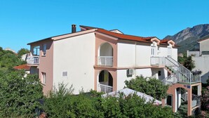 A two-story building with a balcony and a staircase leading to the upper floor. - Cosy apartment for 5 people with A/C, WIFI, TV, balcony and pets allowed (Gradac)