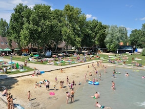 Una playa con gente tomando el sol, nadando y jugando.