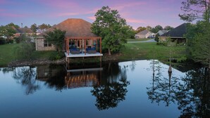 A lakeside house with a covered deck and a stone wall. - Custom Built Lake House (Gulfport)