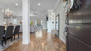 A spacious living room with a high ceiling, wooden flooring, and a chandelier. - Custom Built Lake House (Gulfport)