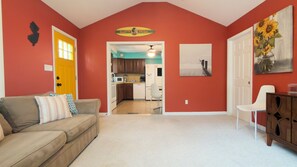 A living room with a beige sofa, a white chair, and a kitchen visible through an open door. - RIPTIDE Family/Pet friendly Bayblock+Walk2Beach🏖 (Villas)