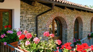 A stone building with arched windows and a tiled roof. - Lovely apartment for 6 guests with pool, TV and terrace (Bonvicino)
