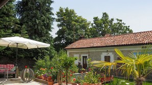 A courtyard with potted plants, a white umbrella, and a stone wall. - Lovely apartment for 6 guests with pool, TV and terrace (Bonvicino)
