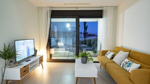 A modern living room with a television, sofa, coffee table, and potted plants. - Ocean Homes Suite 2003 (Punta del Moral)
