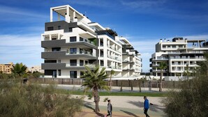 A modern multi-story residential building with balconies and a landscaped area with palm trees. - Ocean Homes Suite 2003 (Punta del Moral)