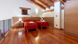 Una habitación con dos camas, suelo y techo de madera, un ventanal pequeño y un armario.