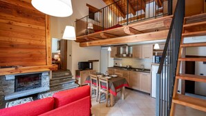 Un salón amplio con chimenea, una mesa de comedor y sofás rojos.
