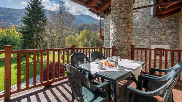 Una terraza con una mesa lista para dos, con vistas a un paisaje montañoso.