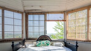 Une chambre à coucher avec un lit, de grandes fenêtres et une vue sur la verdure.