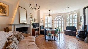 Un salon chaleureux avec une cheminée, un canapé, une table à manger et une grande fenêtre en arc de cercle.