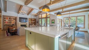 Een ruime keuken met een groot kookeiland, houten balken en hanglampen.