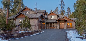 Eine zweistöckige Blockhütte mit Steinfundament, einer Veranda und einer Garage.