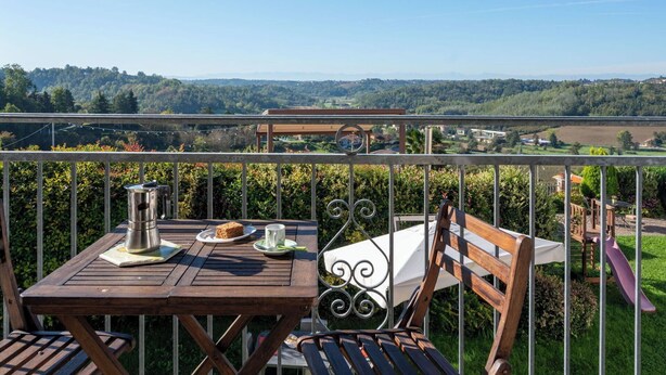 A balcony with a wooden table, a metal chair, and a metal railing. - Beautiful apartment for 4 guests with WIFI, pool, A/C, TV, patio and pets allowed (Cossombrato)