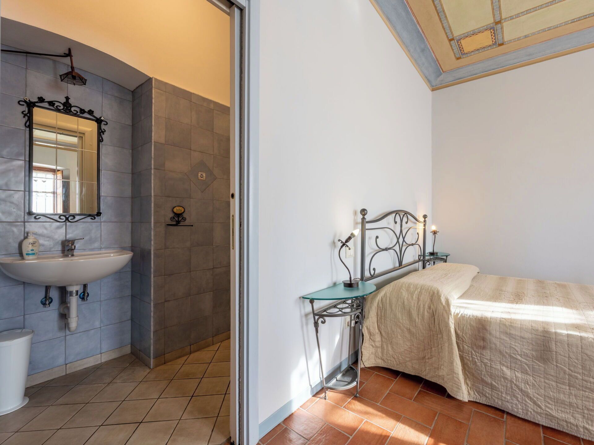 Une chambre à coucher avec un lit, une table de chevet avec des lampes et une salle de bain avec un lavabo et un miroir.