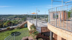 A rooftop terrace with a view of a rural landscape, a brick building, and a metal railing. - Beautiful apartment for 4 people with pool, WIFI, TV, patio and pets allowed (Cossombrato)