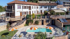 A residential building with a swimming pool, outdoor seating, and a covered patio area.