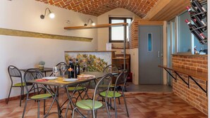 A dining area with a brick ceiling, a brick wall with a leaf pattern, and a wine rack with bottles.