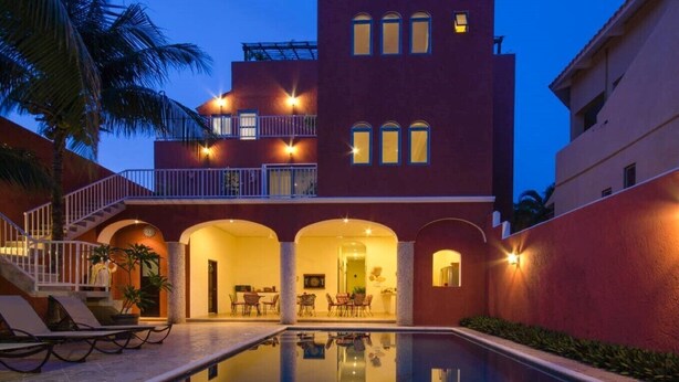 A multi-story building with a swimming pool, outdoor seating, and a staircase leading to a balcony. - Summerplace Inn Condo: Colibri (San Miguel II)