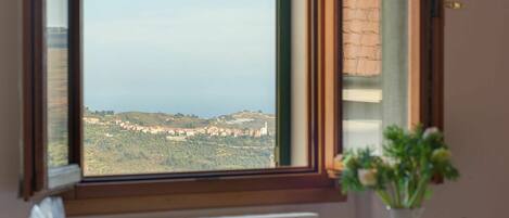 A dining table with breakfast items and a view of a coastal landscape through a window.