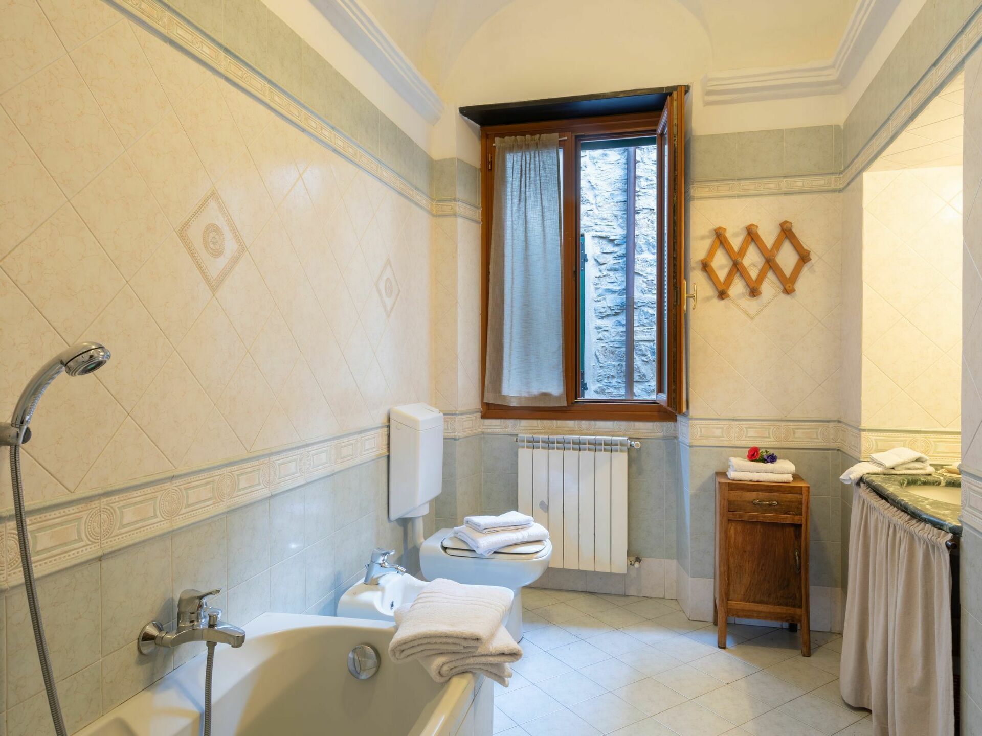 A bathroom with a bathtub, toilet, and a window with curtains.