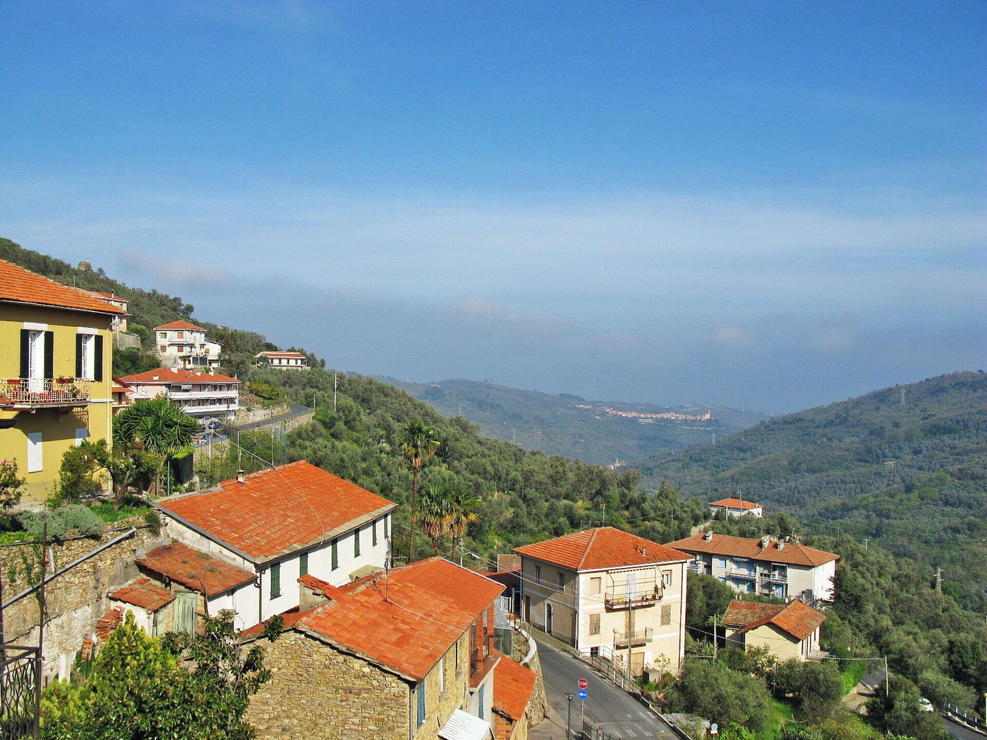 A hillside village with traditional stone buildings and red-tiled roofs.