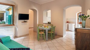 Ein gemütliches Zimmer mit Esstisch, Stühlen, Fernseher und einer Küchenzeile.