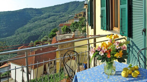 Ein Balkon mit Tisch, Blumen und Zitronen.
