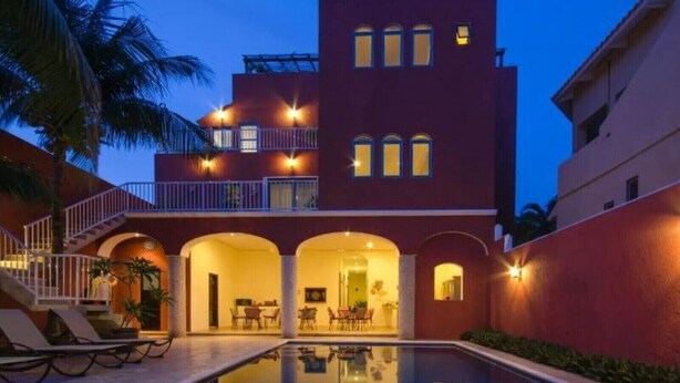 A multi-story hotel with a swimming pool, outdoor seating, and a well-lit entrance. - summerplace inn      (San Miguel II)
