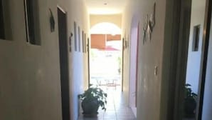 A narrow hallway with tiled flooring, a potted plant, and a glass door on the right. - summerplace inn      (San Miguel II)