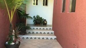A building with a red exterior, a tiled patio, and a staircase leading to a door with two windows. - summerplace inn      (San Miguel II)