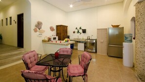 Angolo cottura compatto con zona pranzo, caratterizzato da un tavolo centrale con sedie, un frigorifero e un forno a microonde.