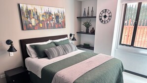 Un dormitorio moderno con una cama, mesitas de noche, un reloj de pared, un cuadro de un paisaje urbano y una ventana con vistas.