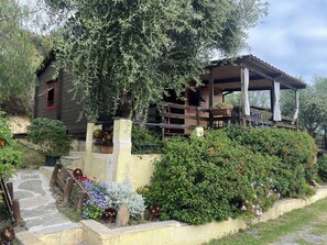 A rustic wooden house with a covered porch, stone steps, and a variety of flowering plants. - Beautiful apartment in villa for 4 people with pool, A/C, patio, pets allowed and panoramic view (Costarainera)