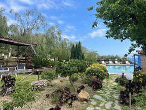 A garden with a pool, outdoor seating, and various plants. - Beautiful apartment in villa for 4 people with pool, A/C, patio, pets allowed and panoramic view (Costarainera)