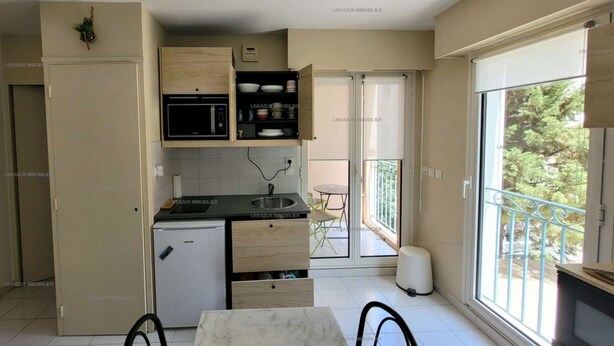 A compact kitchen with a refrigerator, microwave, and sink. There is a small dining area with a table and chairs.